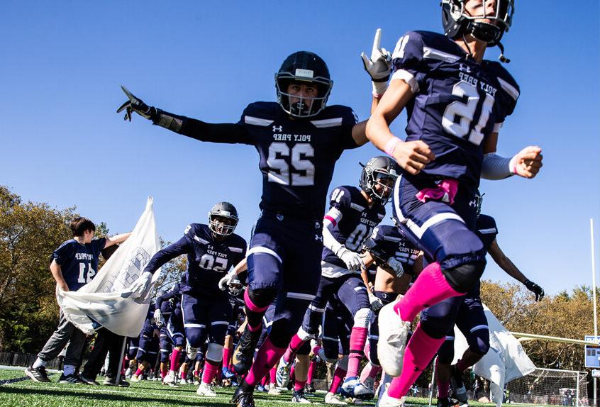 保利预科 大学运动代表队 足球 Team breaking through a banner at the Homecoming game